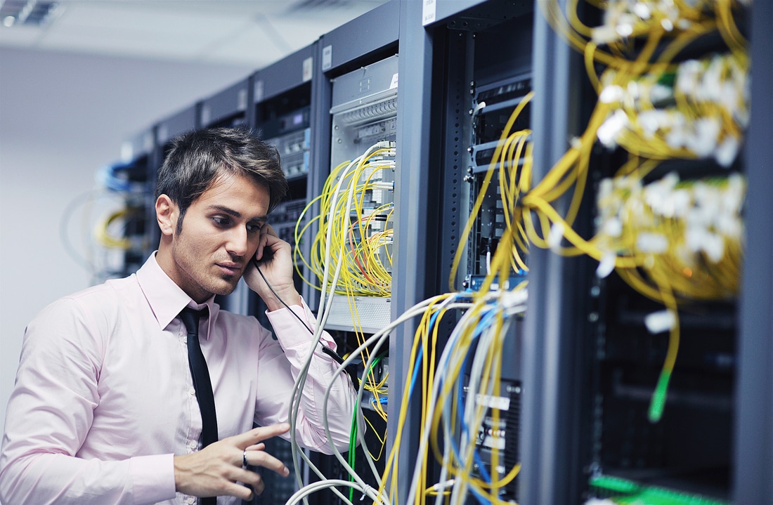 Male business professional in a server room calling IT support to fix a technical problem