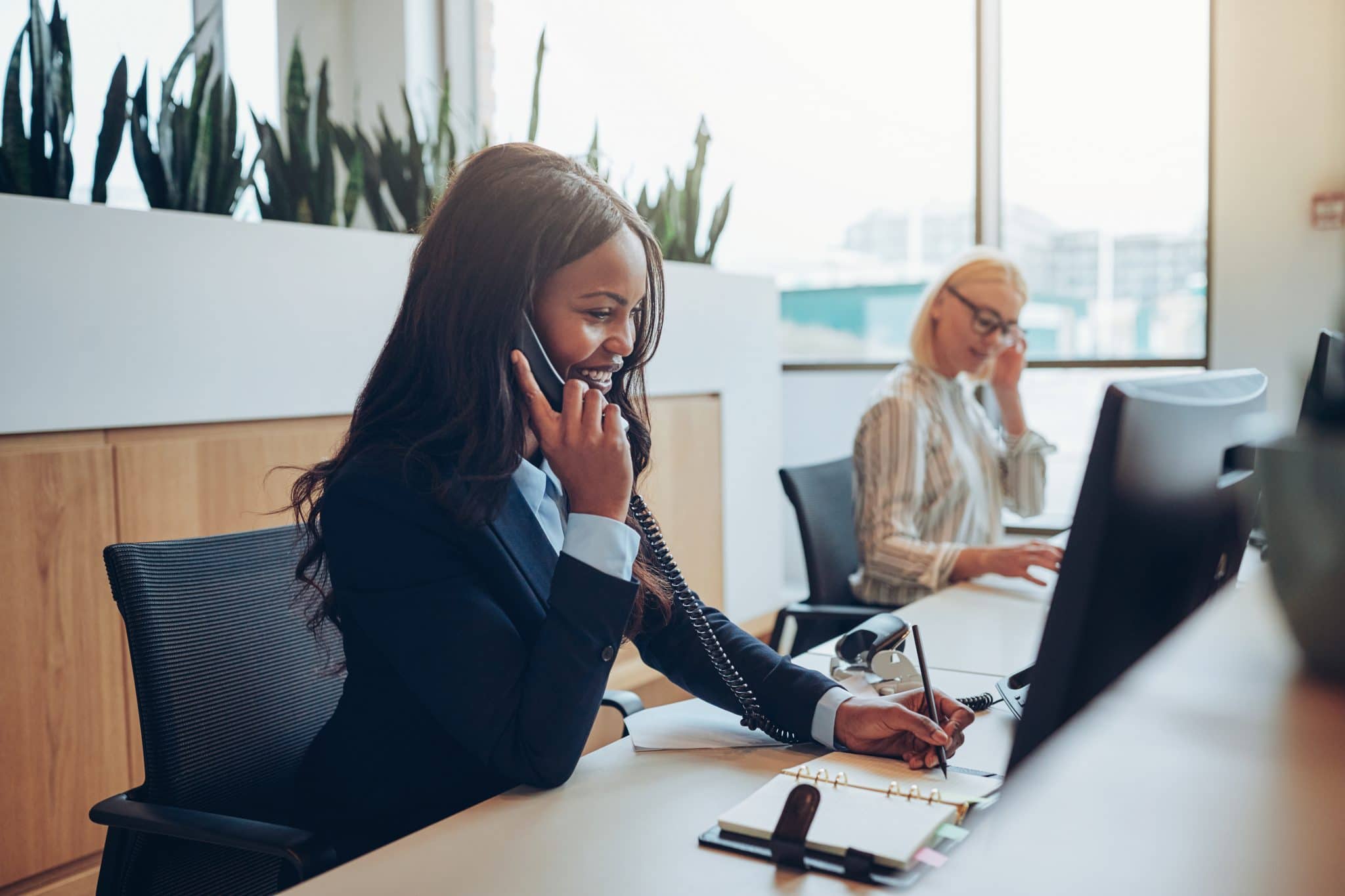 Female insurance policy specialist at desk on the phone with client