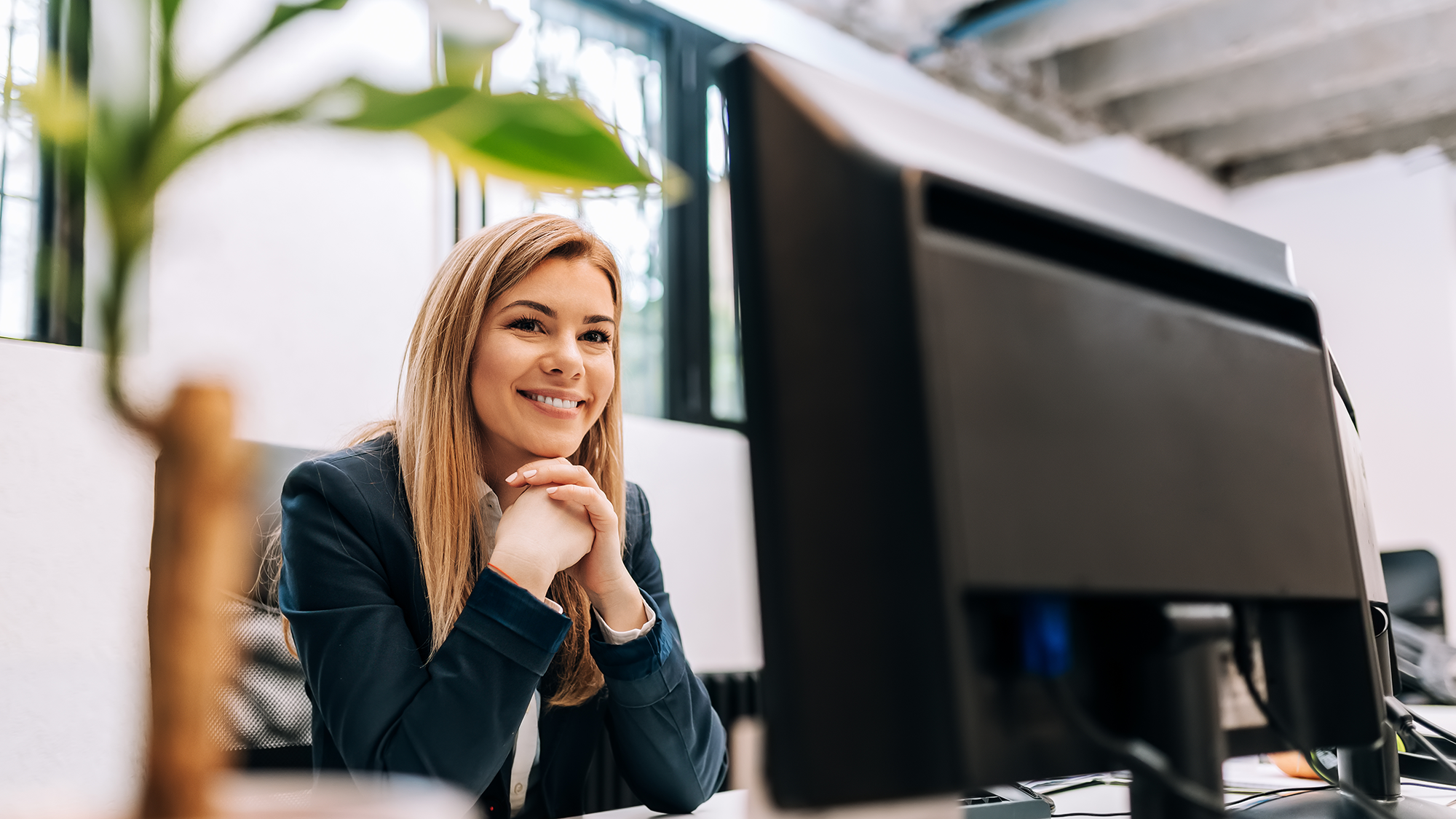 Smiling businesswoman in front of desktop computer