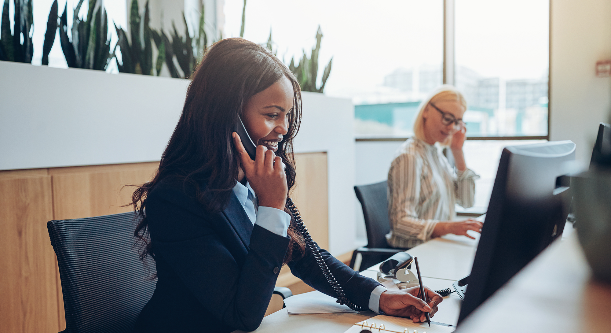 Female insurance policy specialist at desk on the phone with client