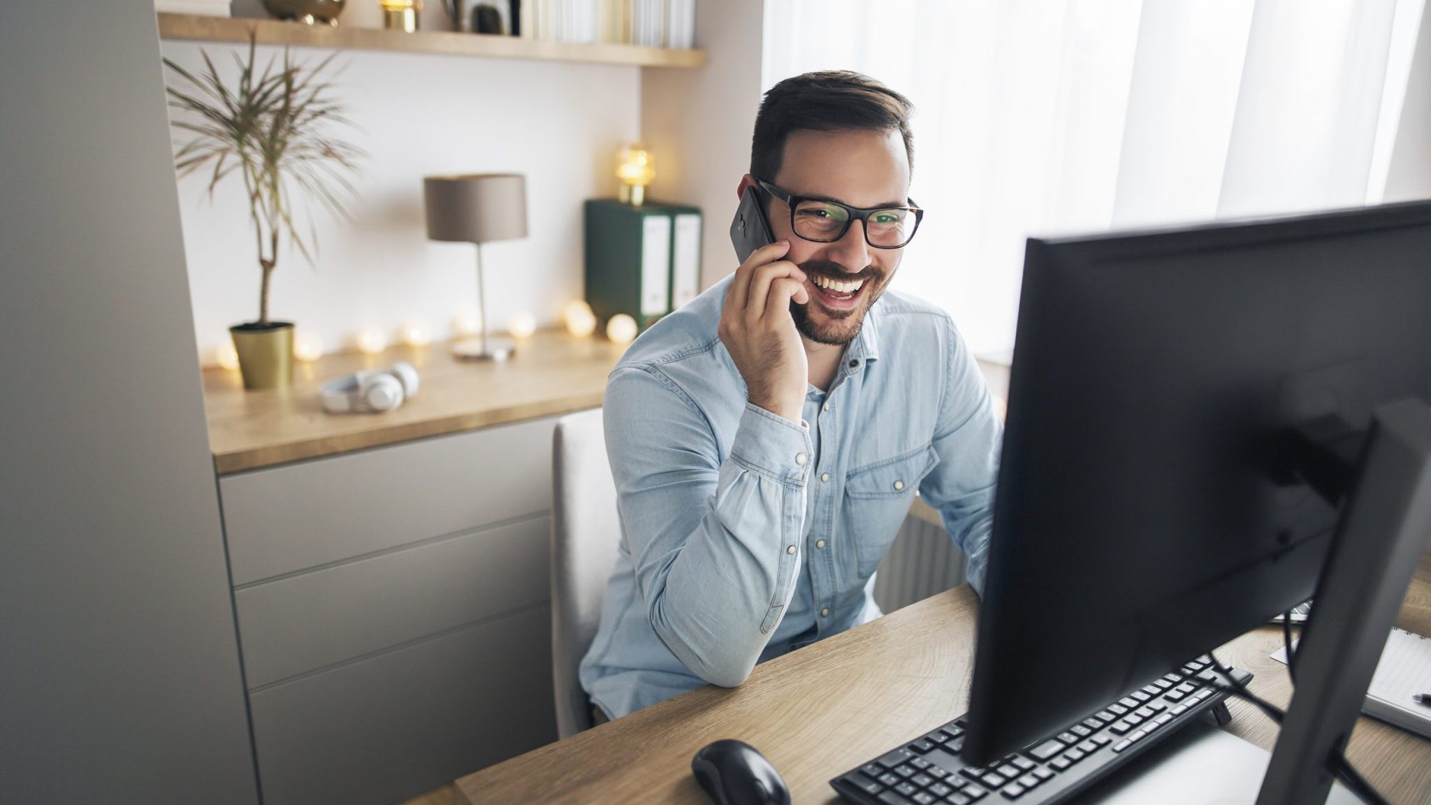 Happy manager on cell phone calling client from home office